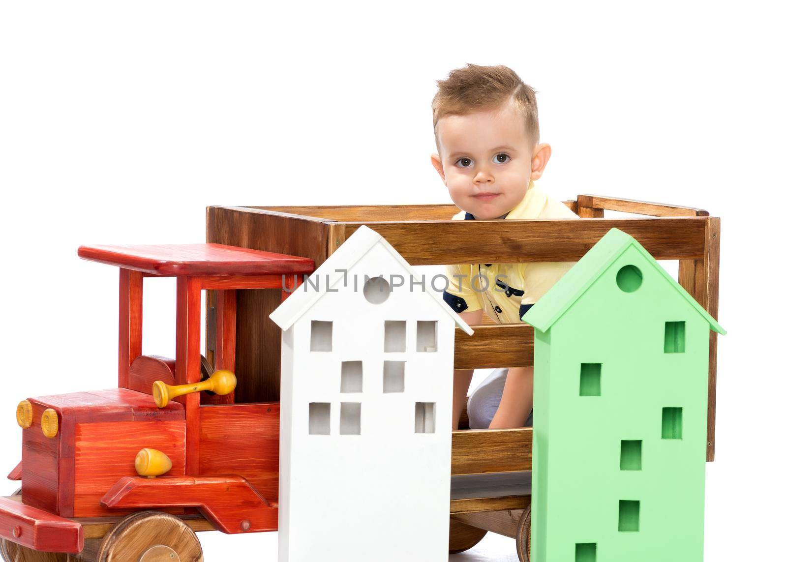 Cute little boy is playing with a toy wooden car on a white background in the studio. The concept of a happy childhood, learning and education in the family. Isolated.