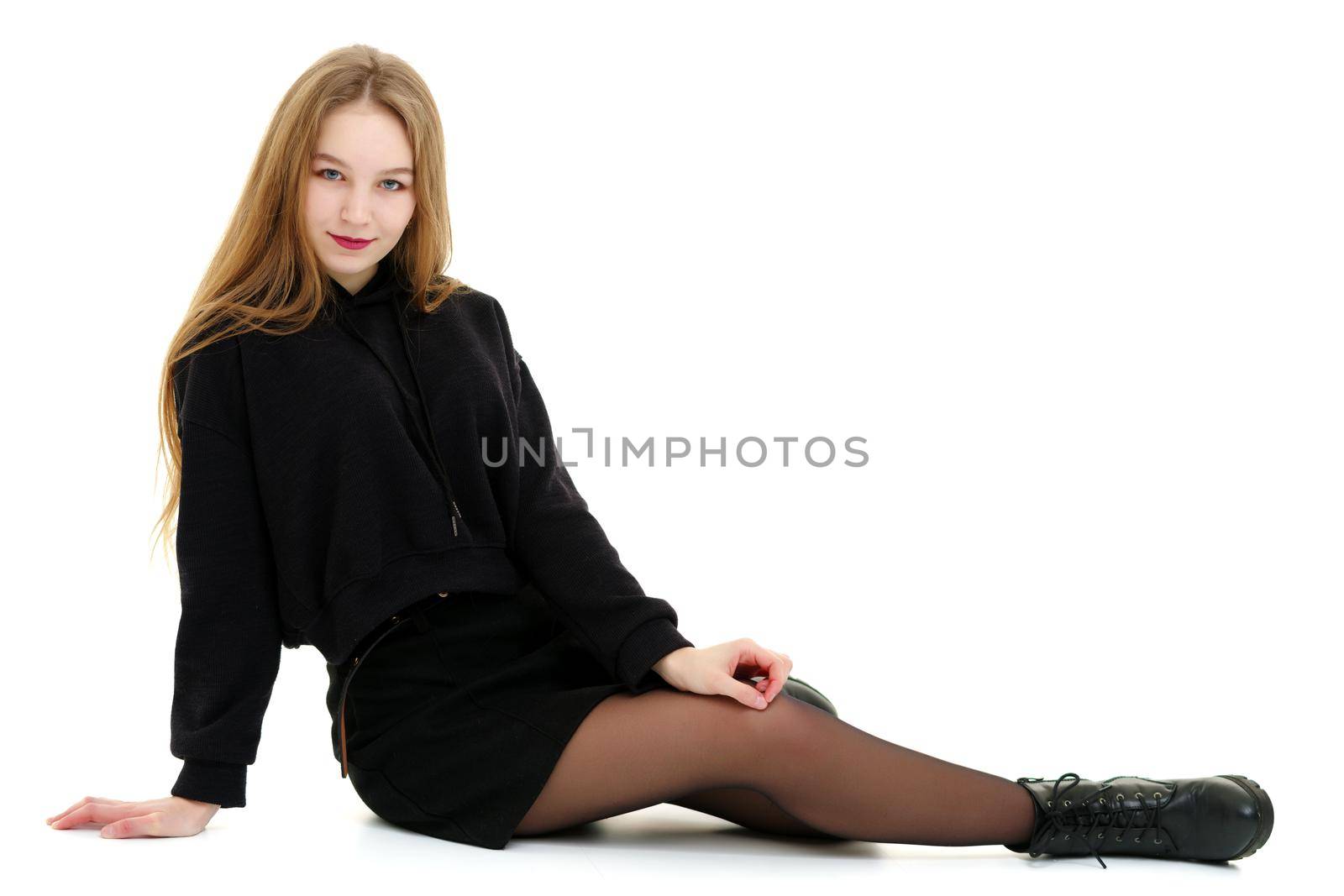 A beautiful teen girl sits on the floor on a white background. The concept of education and schoo. Isolated.