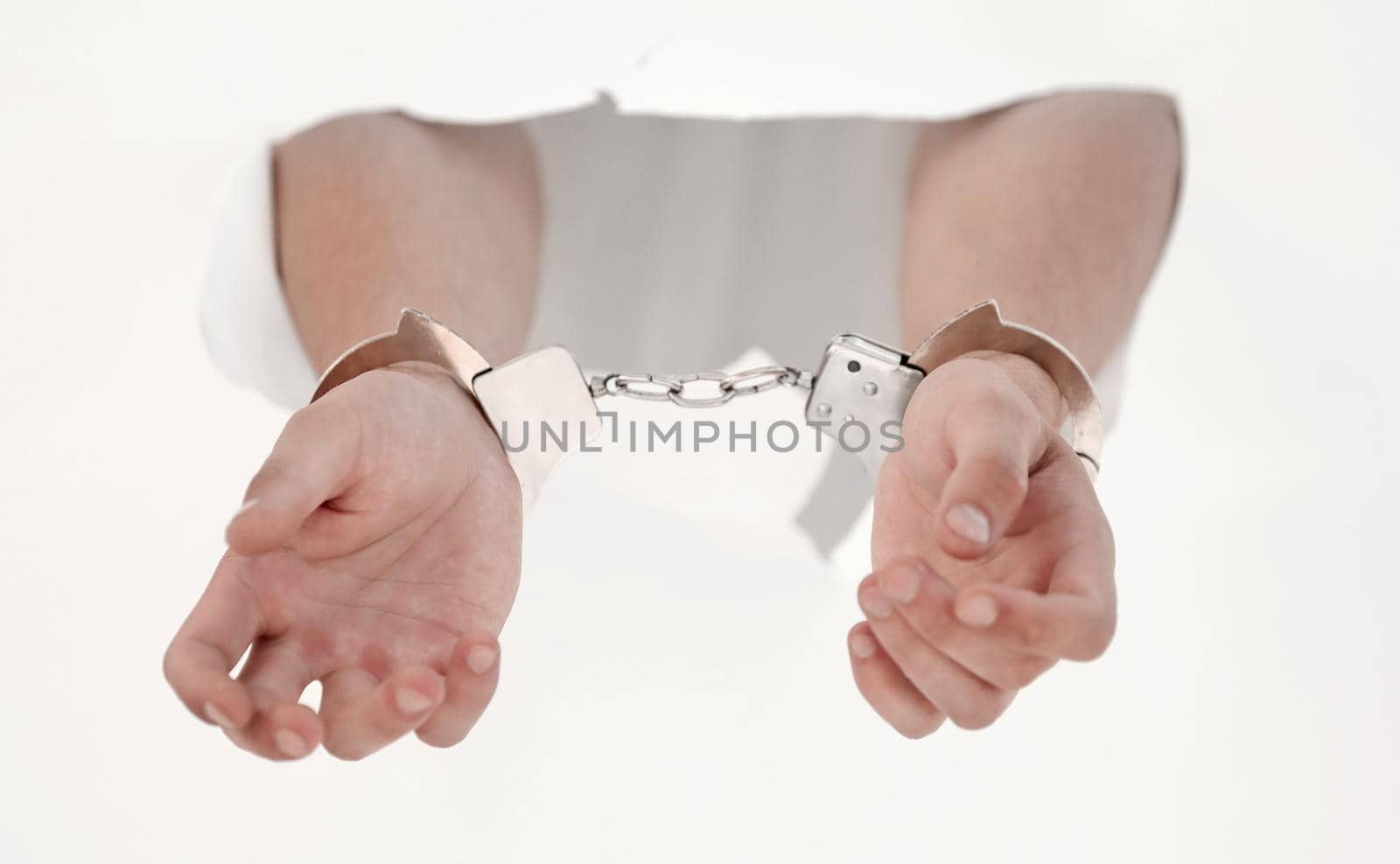 Handcuffs on the hands of a man breaking a paper wall.photo with copy space