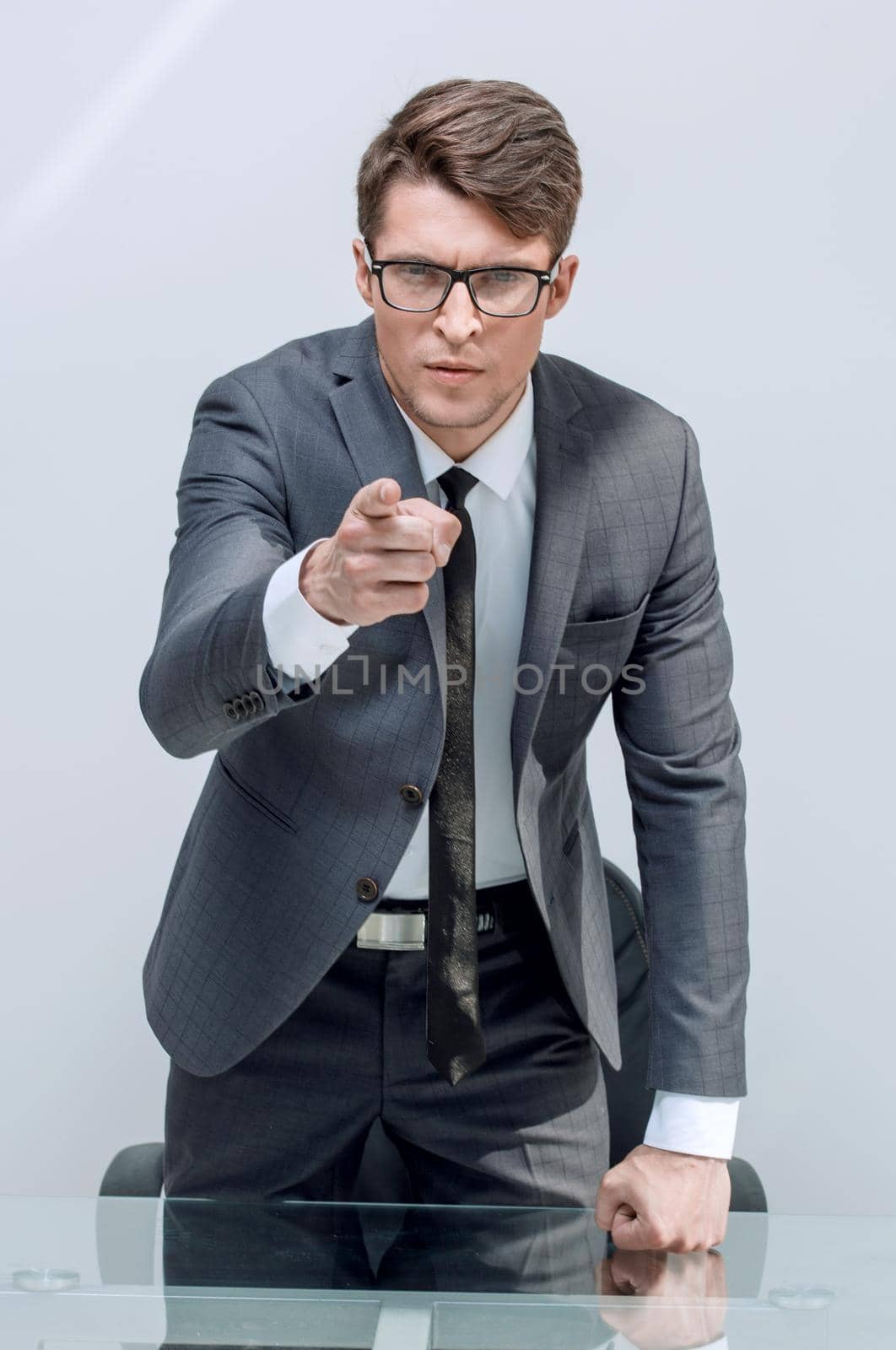 close up.strict businessman standing near the desktop.isolated on light background