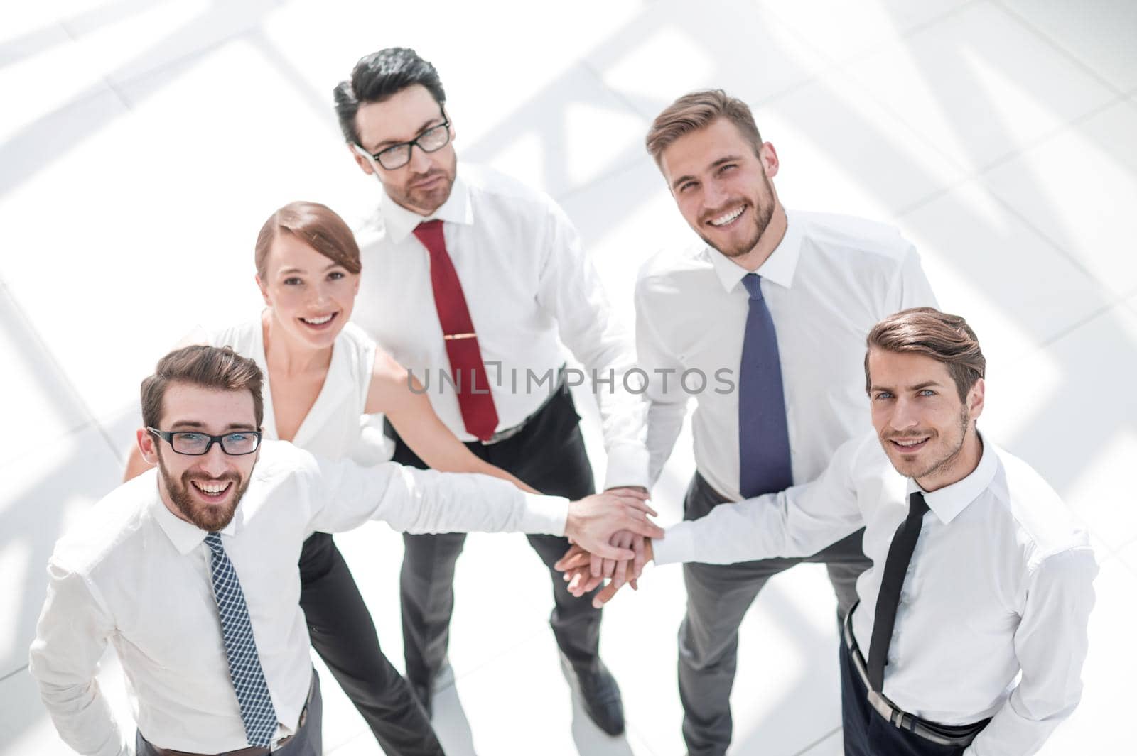 young employees standing in a circle and folding their hands together. photo with copy space