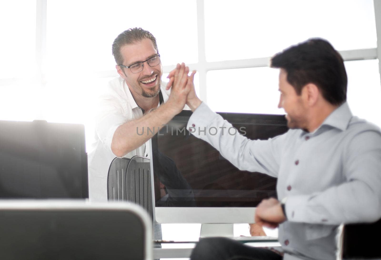 employees give each other a high five over the computer Desk by asdf
