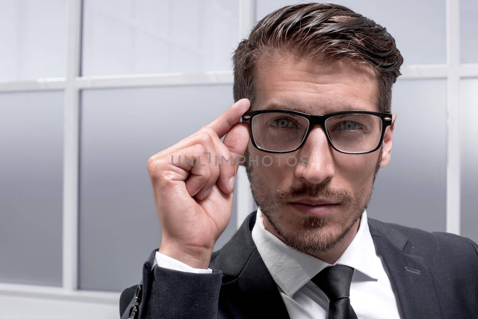 young successful businessman with a serious face stands in the office in a business suit