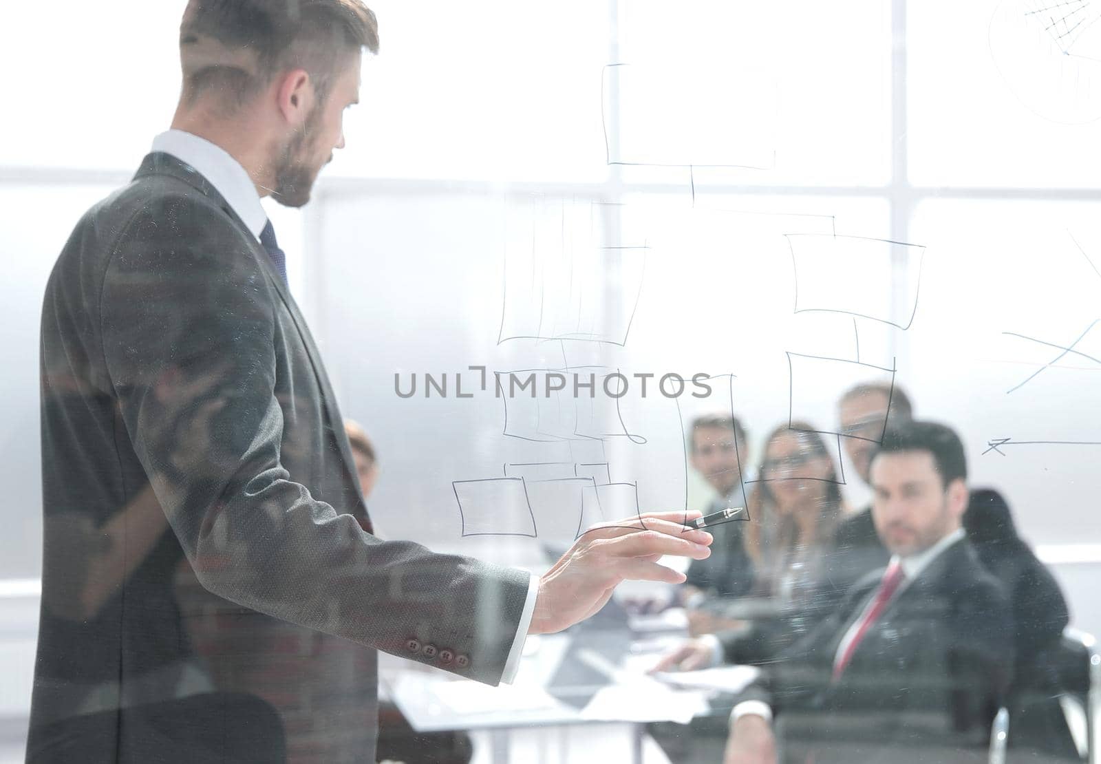 Focused caucasian business people meeting in boardroom behind glass.