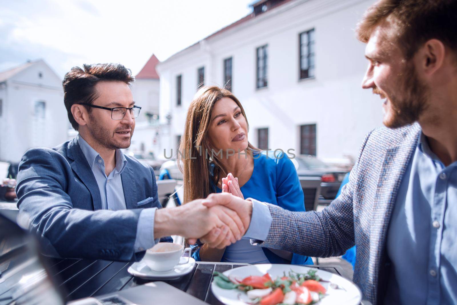 colleagues greeting each other with a handshake in the cafe by asdf