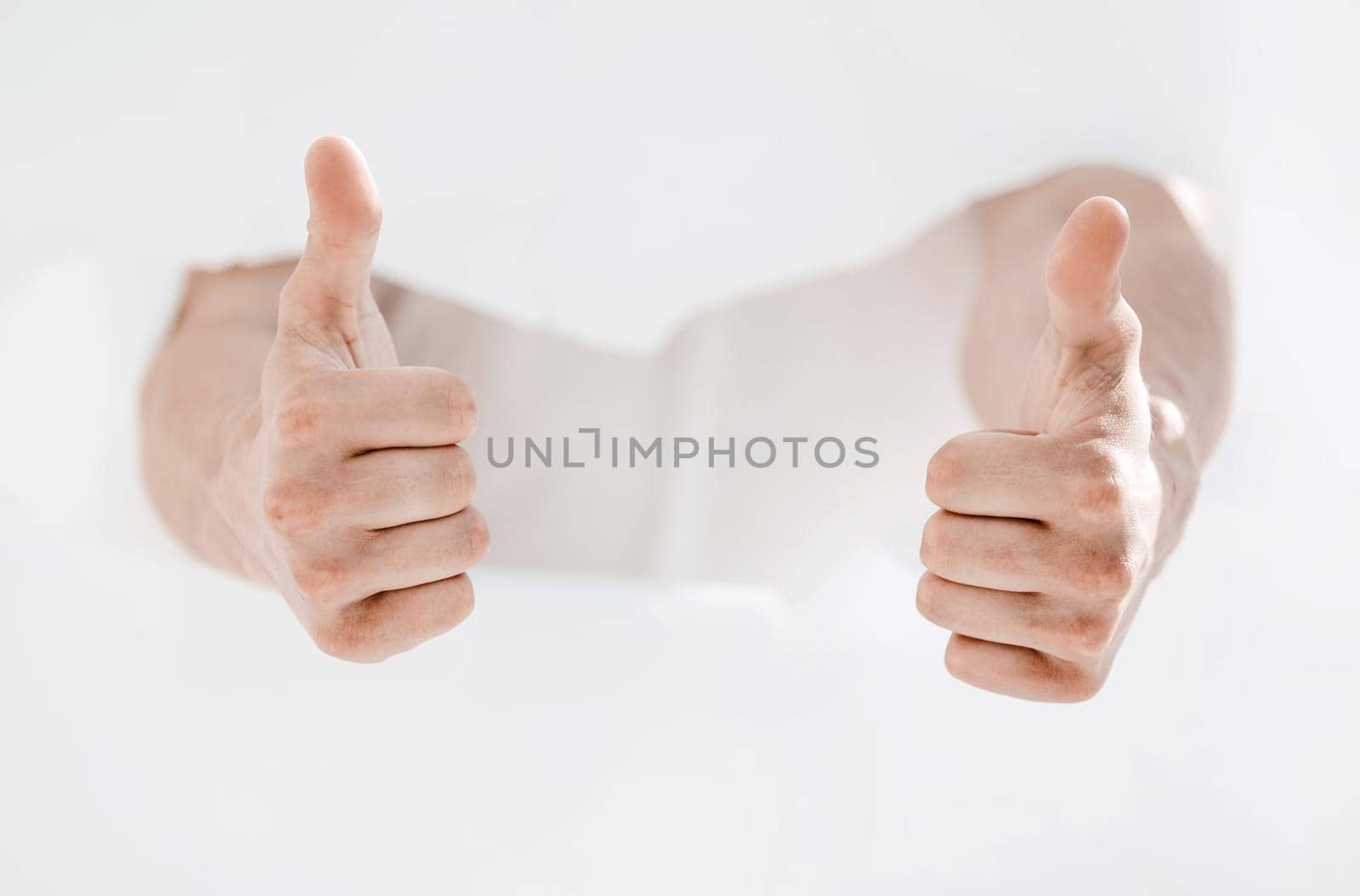 man breaking through the paper wall and showing thumbs up.photo with copy space