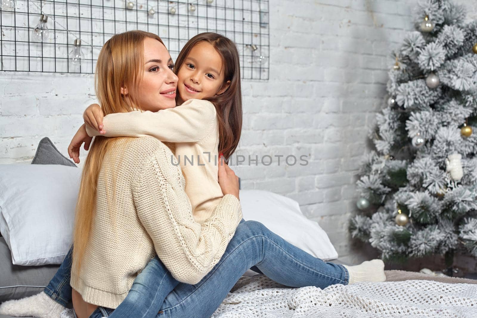 Beautiful young woman and her charming little daughter are hugging. by nazarovsergey