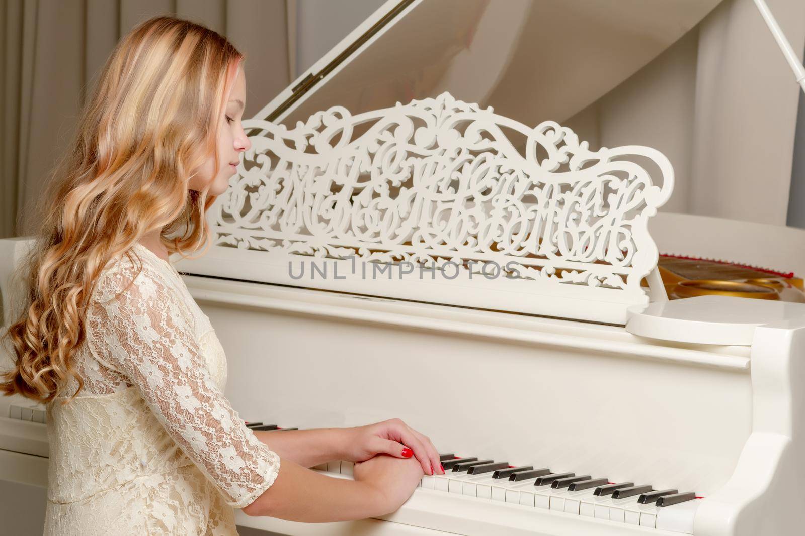 A teenage girl is playing on a white grand piano. The concept of creative development of personality, music education.