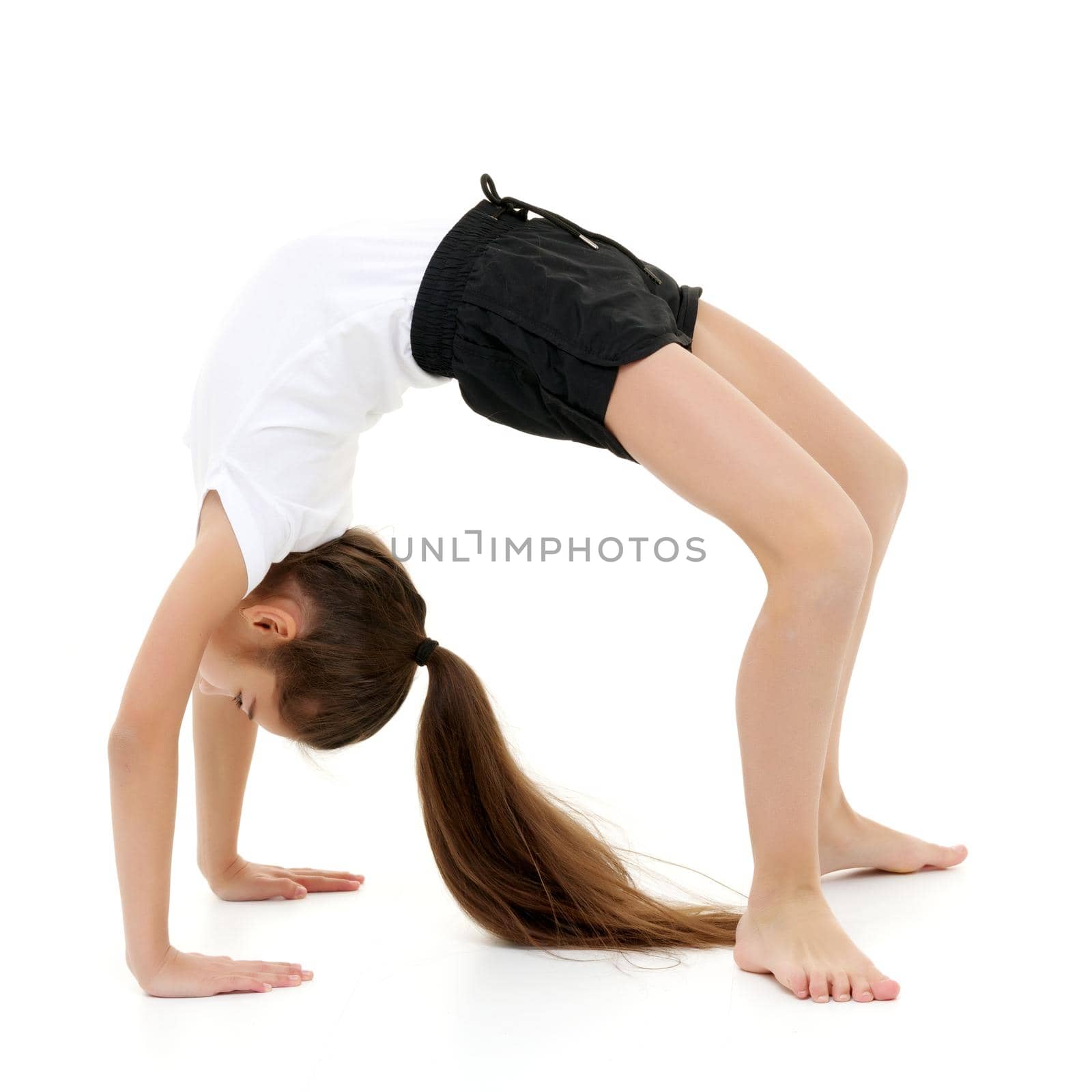 A little girl gymnast performs a bridge. The concept of childhood, sport, healthy lifestyle. Isolated on white background.