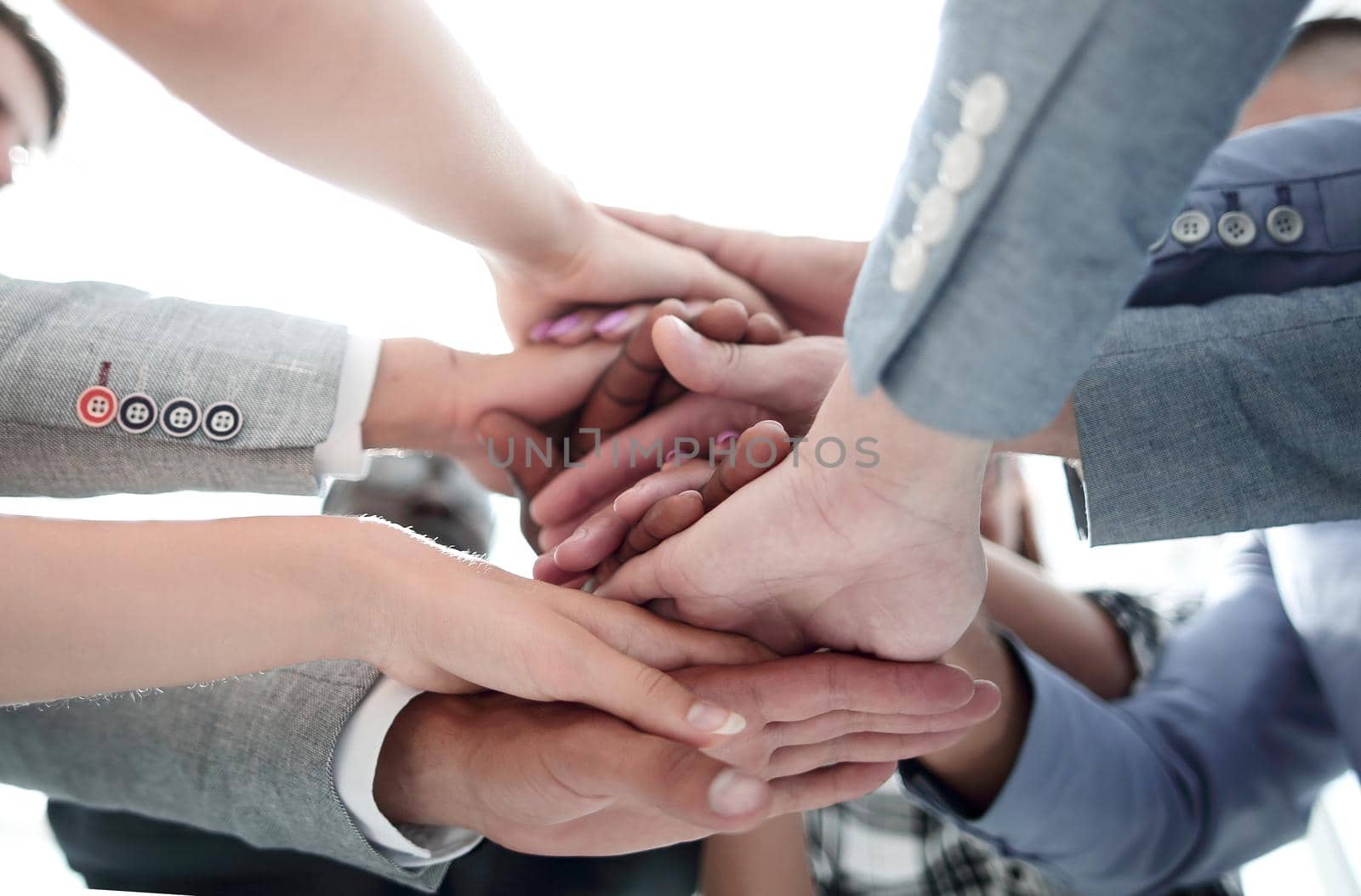 multiracial businessmen stack their hands on each other standing in the office