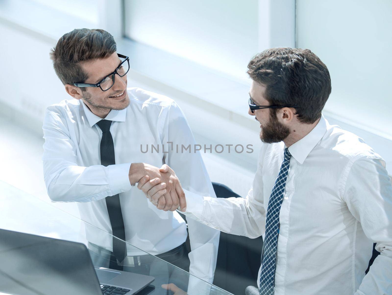 close up.employees shaking hands at the Desk.people and technology