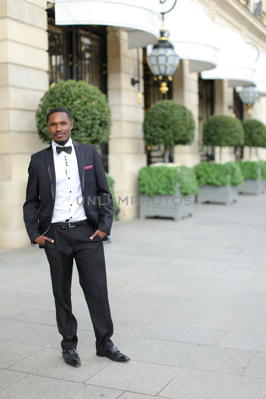 Afro american successful man wearing suit and standing near building. by sisterspro