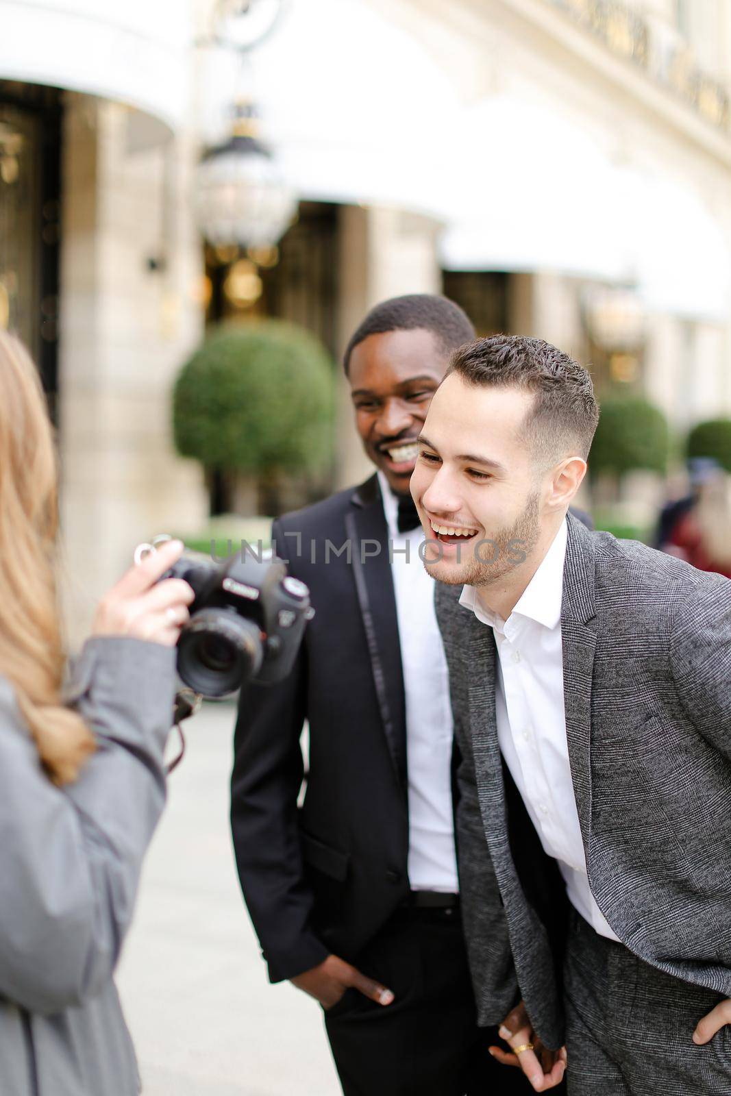 Afro american and caucasian men standing near female photographer with camera. Conceptof gay photo session and business.