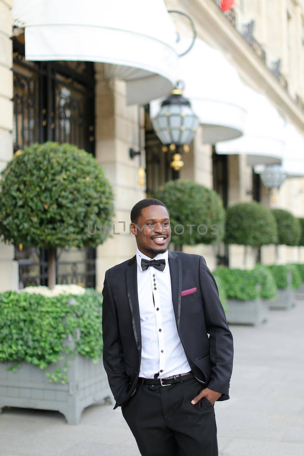 Afro american smiling man wearing suit and standing near building. by sisterspro