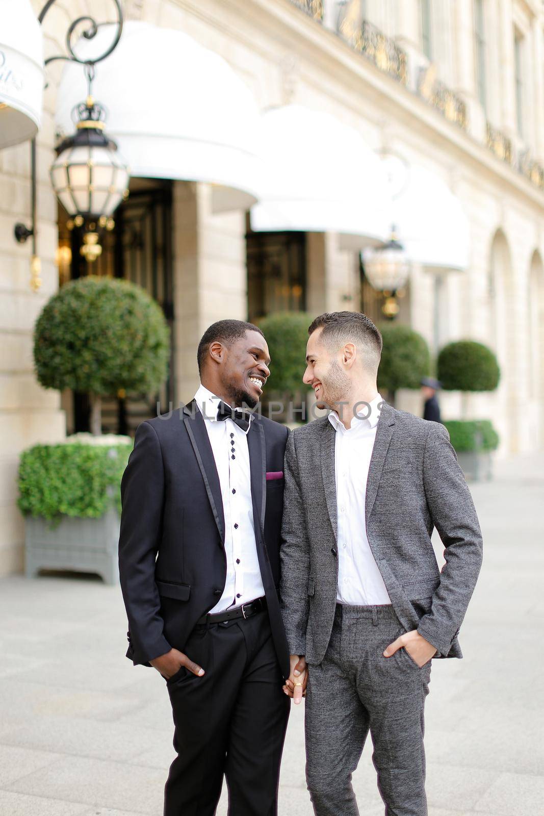 Afro american and caucasian happy gays walking outside in city. Concept of same sex male couple.