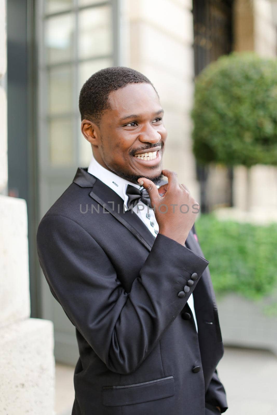 Afro american happy good looking male person wearing suit and smiling outside. Concept of black businessman.