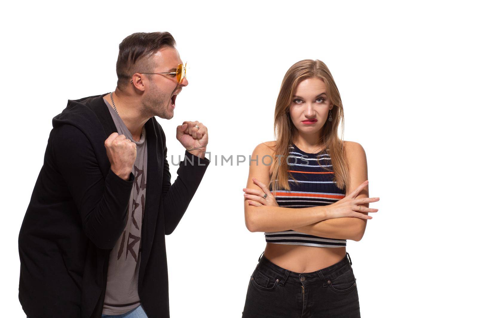 Young emotional man and woman quarrel. Man screaming at the woman waving her arms on white background