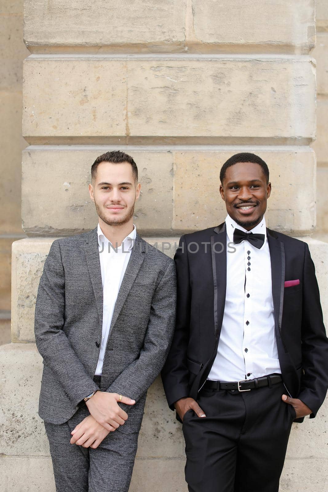 Afro american and caucasian gays standing near building. by sisterspro