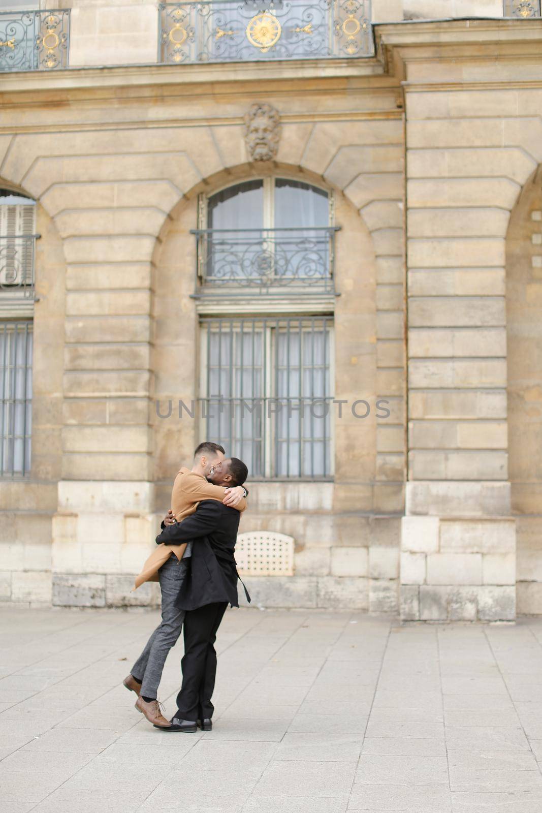 Afro american man holding caucasian guy and waling in city. by sisterspro