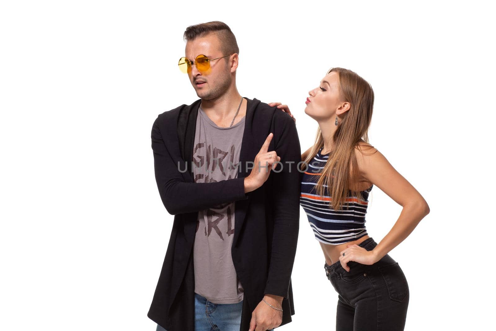 Young woman trying to kiss a young man. Isolated on white background. Studio shot
