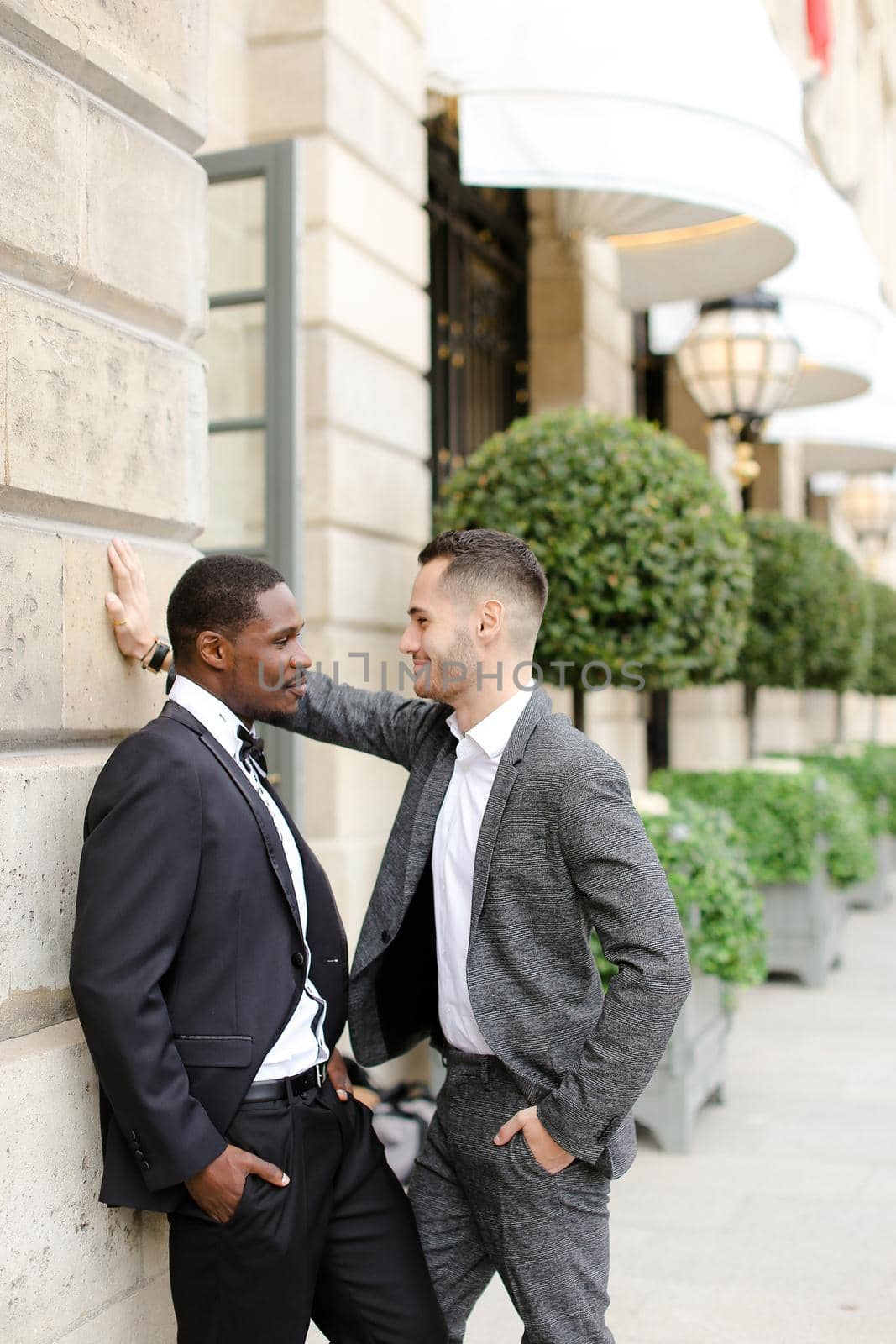 Afro american and european gays standing near building and talking outside. Concept of lgbt and walking in city.