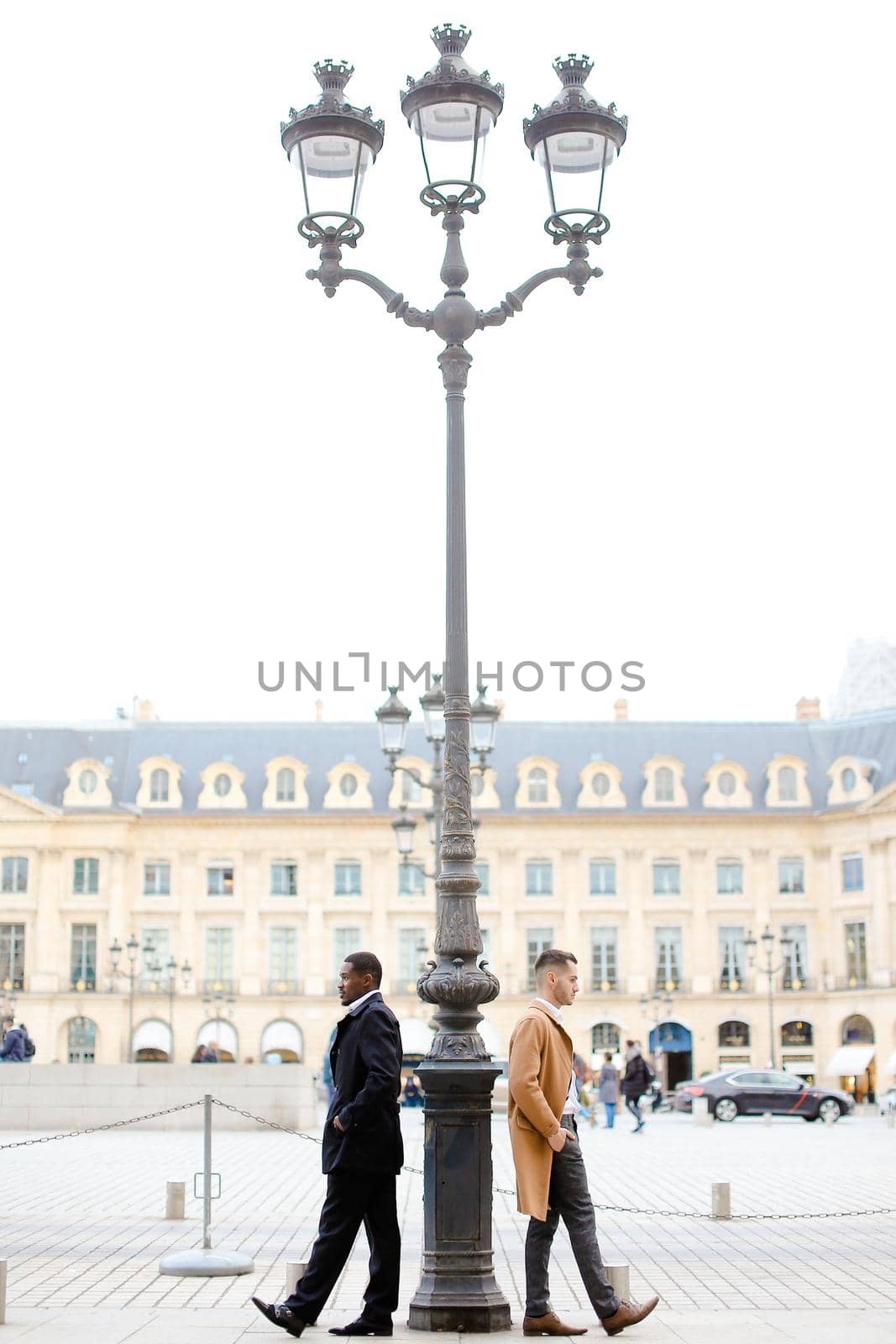 Afro american and caucasian boys standing near street lantern, wearing suits. Concept of urban photo session and life style.