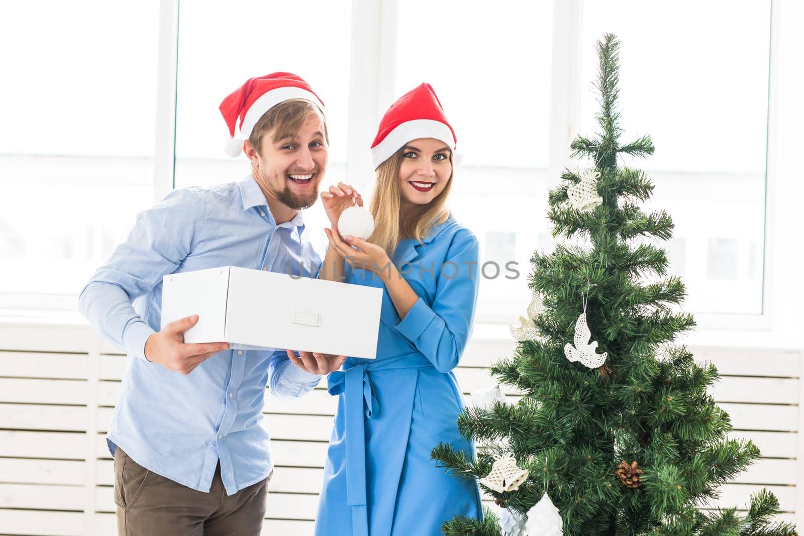 Holidays and festive concept - Young family couple decorating the christmas tree.