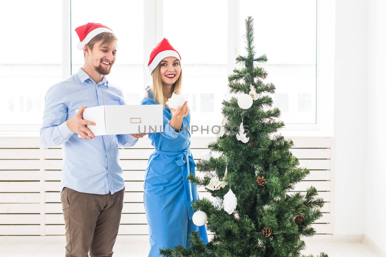 Holidays and festive concept - Young family couple decorating the christmas tree.