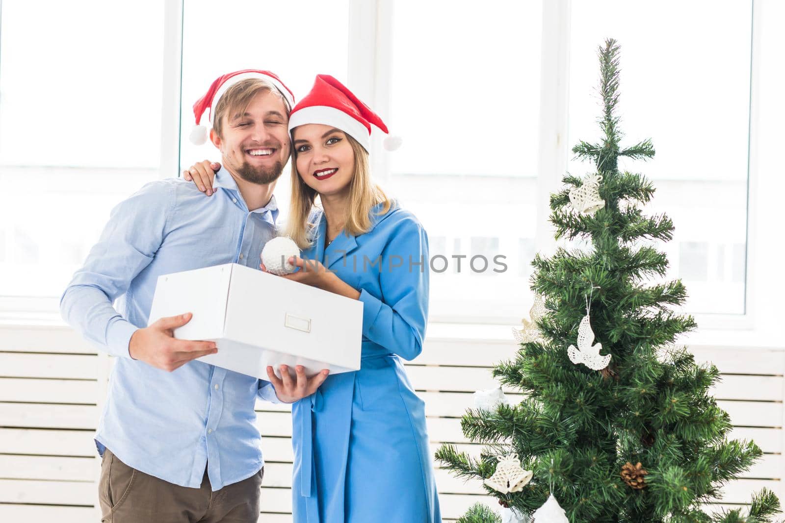 Holidays and festive concept - Young family couple decorating the christmas tree.