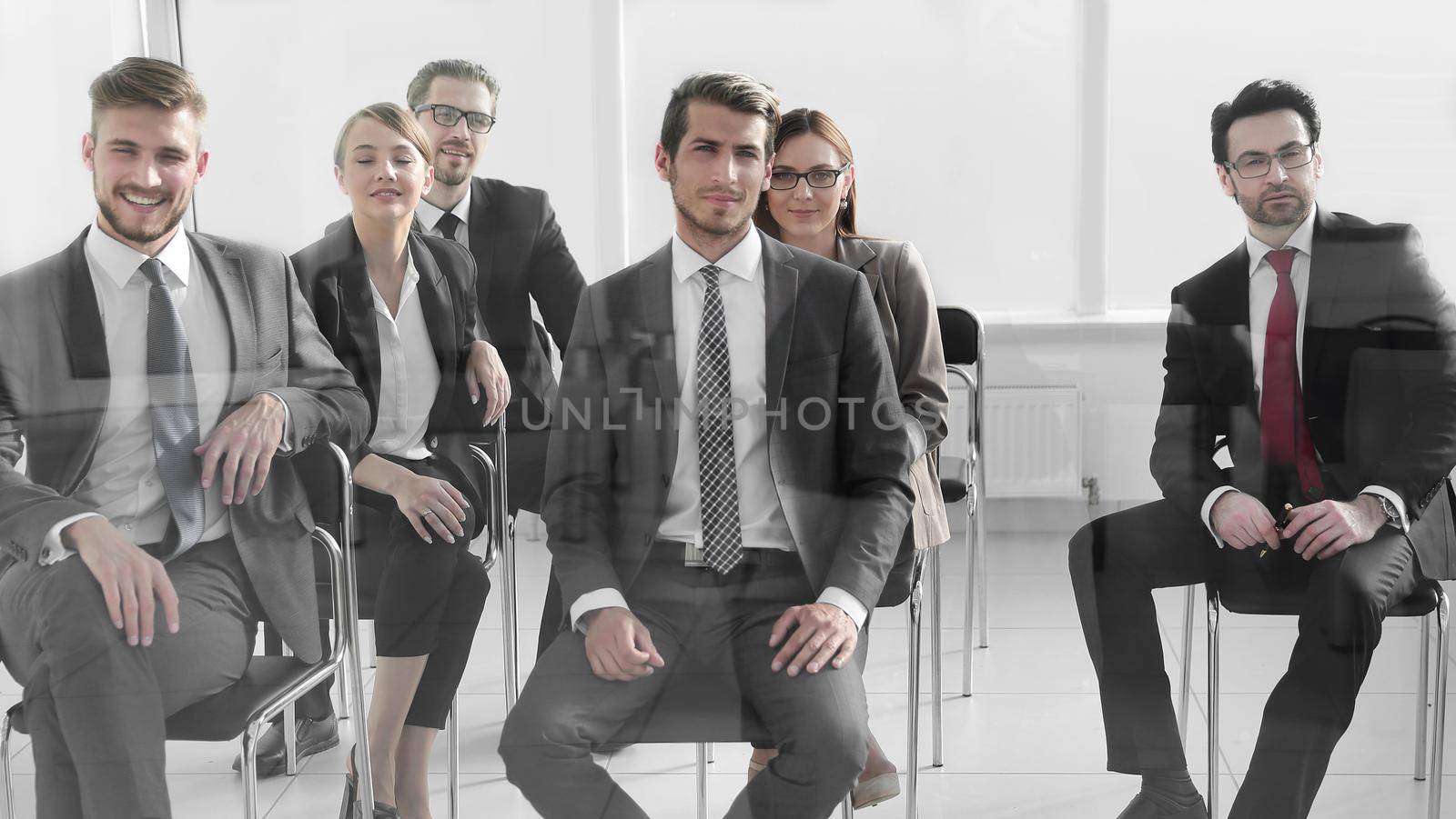 Man and women sitting on chairs in row by asdf