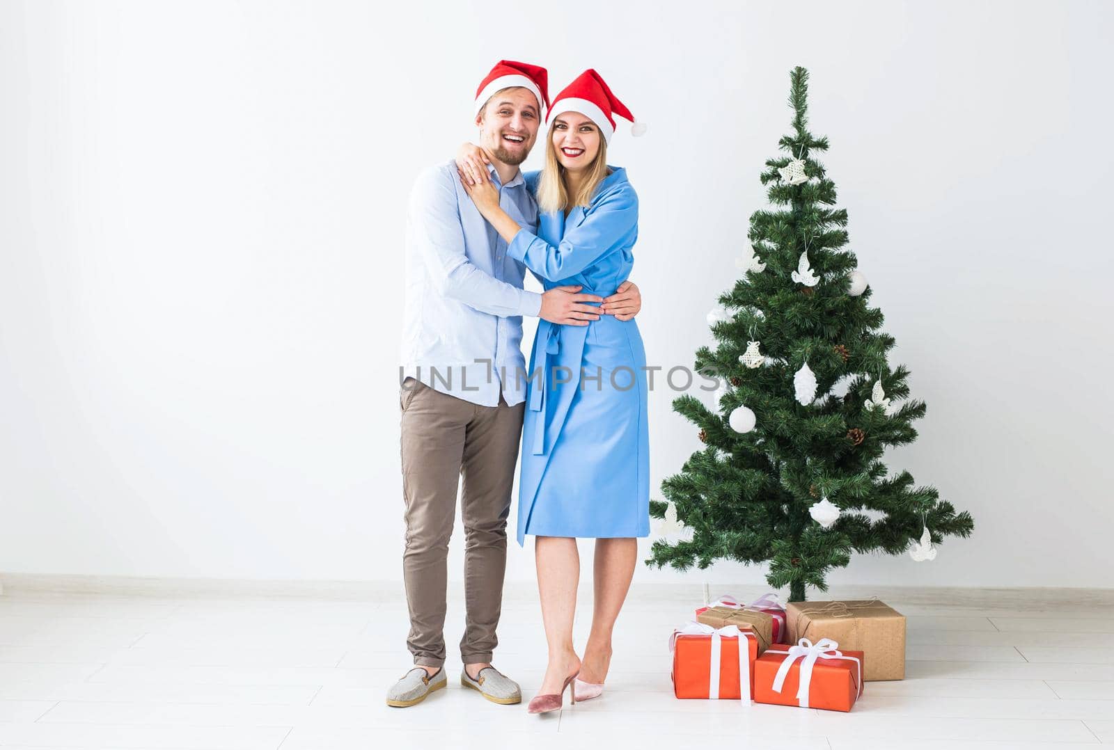 Holidays and celebration concept - Young couple celebrating Christmas at home by Satura86