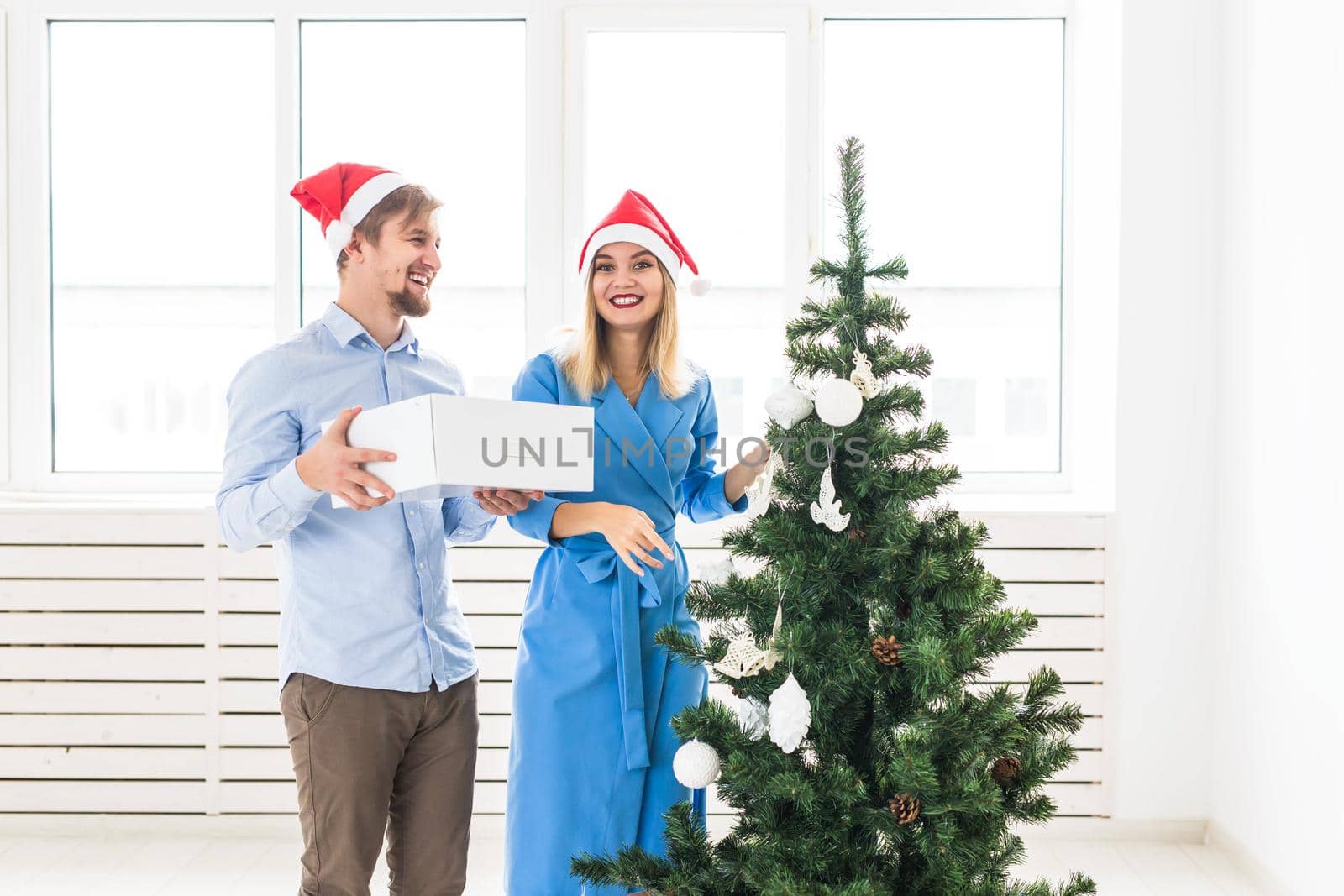 Holidays and festive concept - Young family couple decorating the christmas tree.