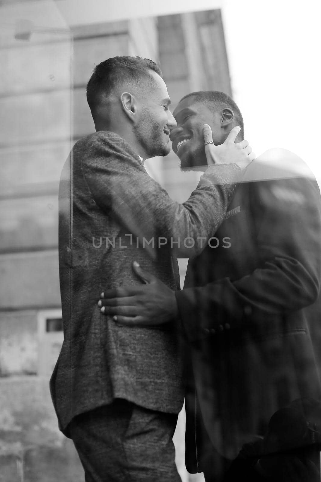 Black and white reflection in window of two happy kissing boys, afro american and caucasian. Concept of gays and lgbt.