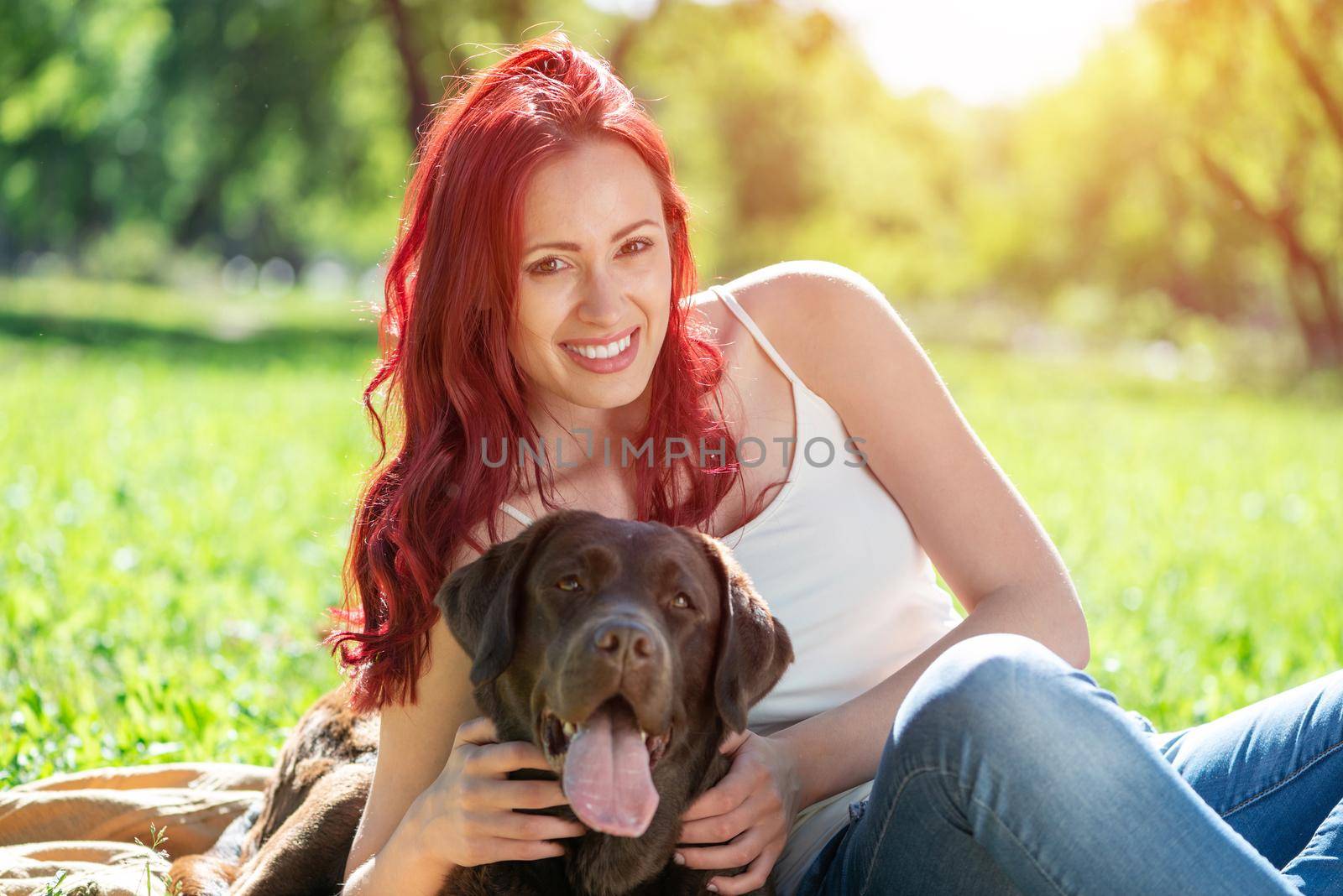 Young attractive woman hugs her dog in the park. by adam121