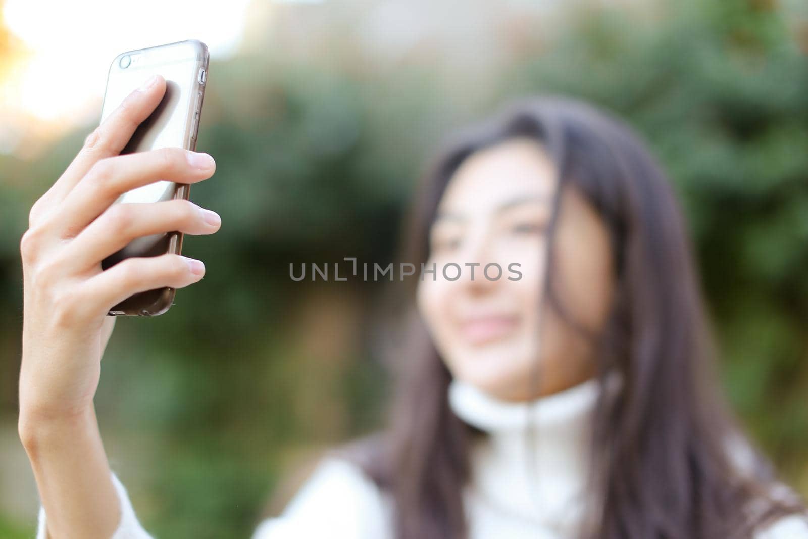 Focus on smartphone, blurred asian girl making selfie. by sisterspro