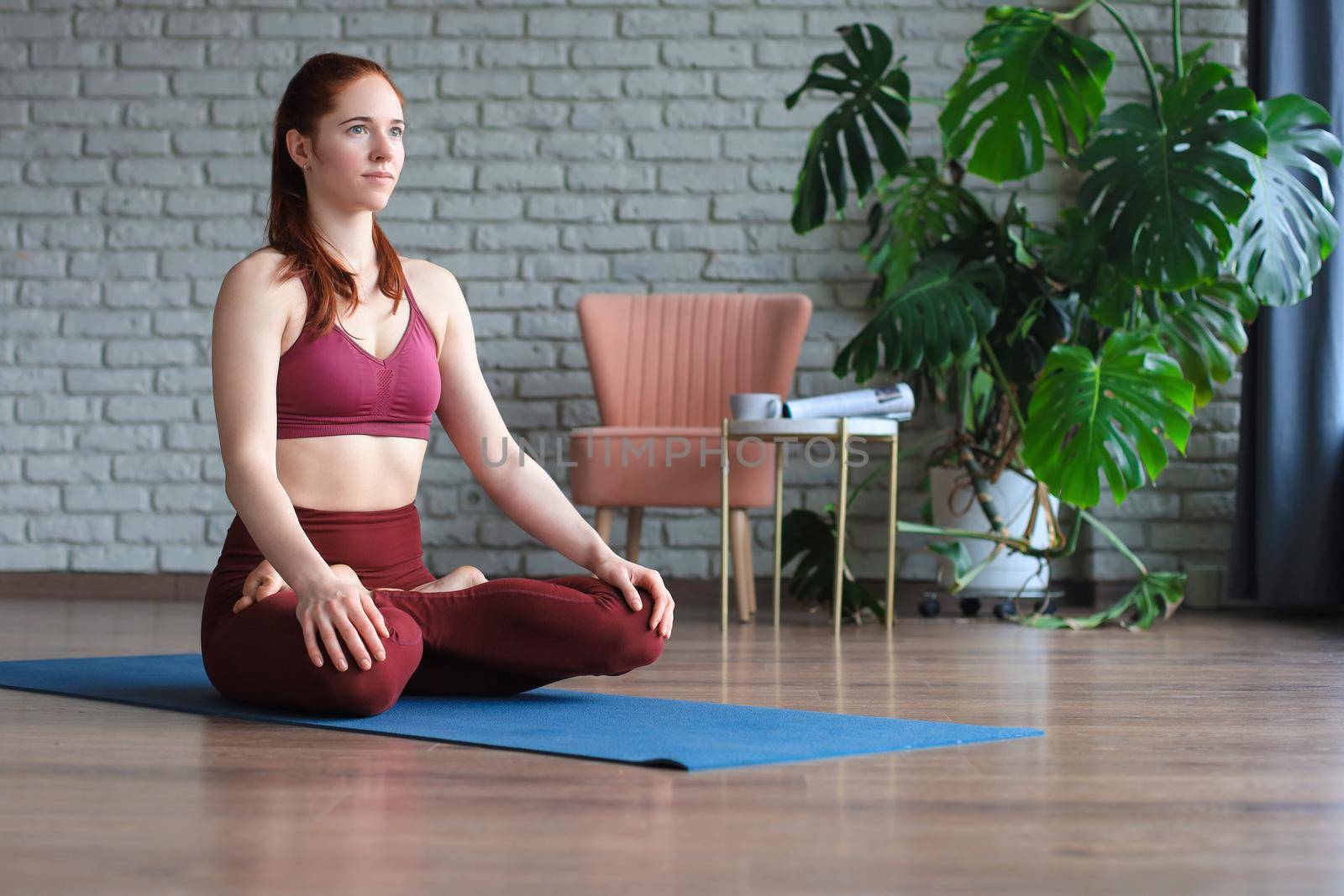 Beautiful woman sitting in lotus pose and meditating at yoga studio. by tsyhun