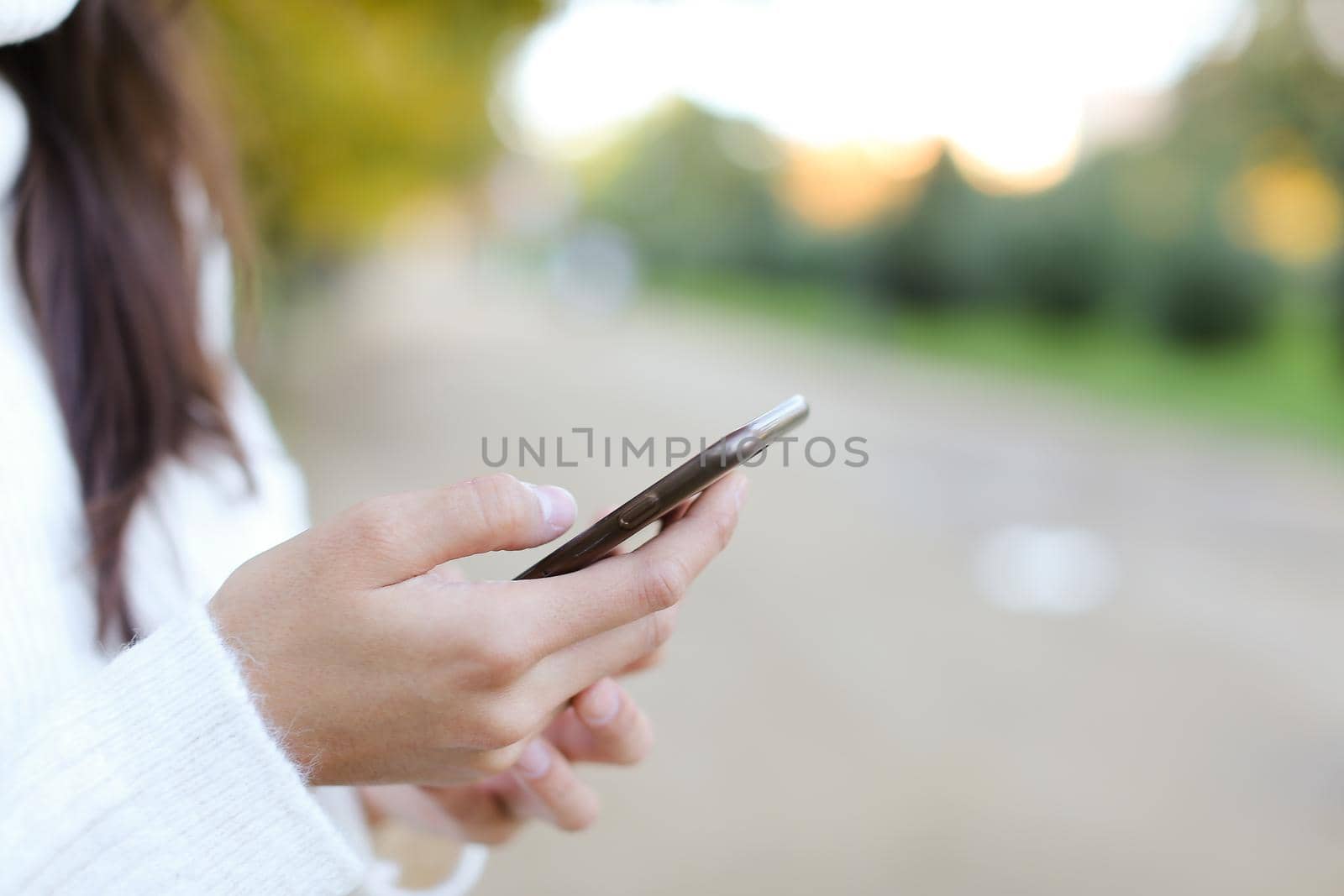 Focus on smartphone in woman hands outside. Concept of modern technology and mobile phone.