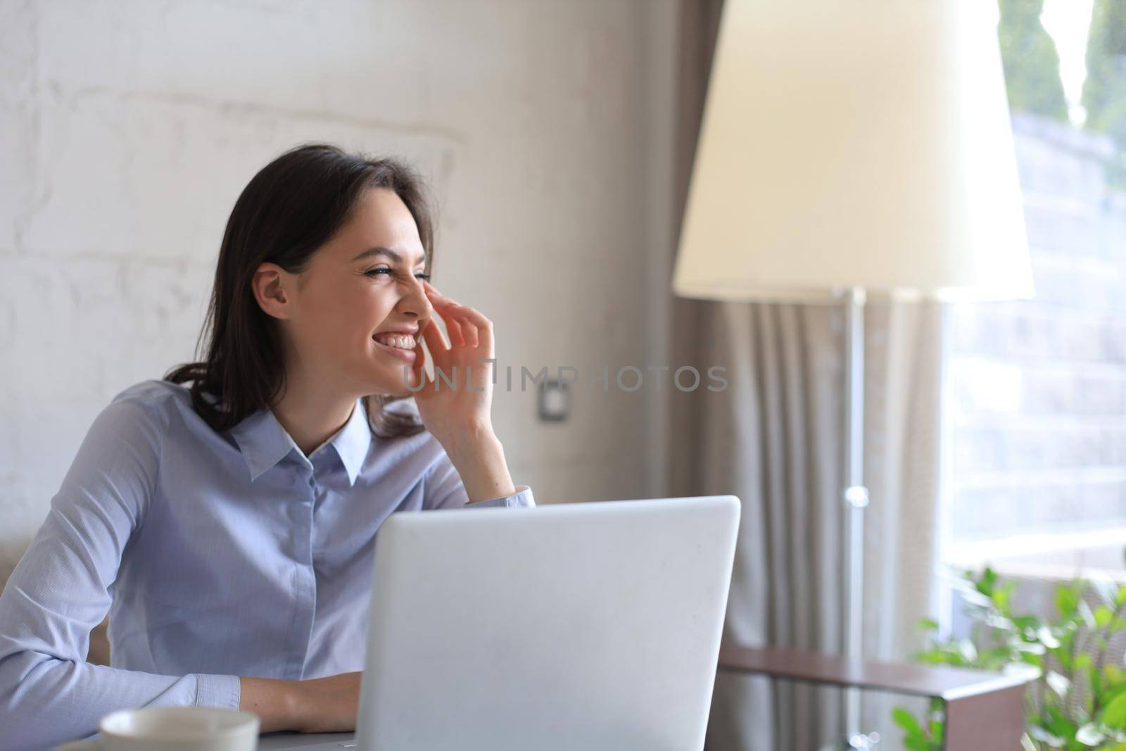 Confident young businesswoman with a friendly smile sitting at her desk in a home office