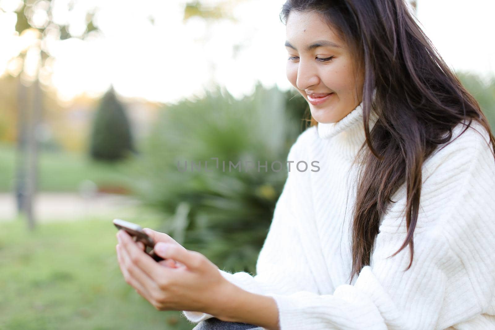 Focus on korean woman keeping smartphone and smiling. Concept of asian modern technology.