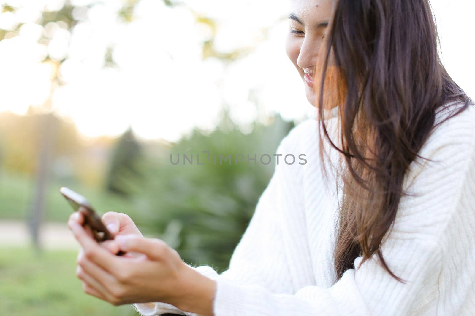 Focus on chinese woman keeping smartphone and smiling. Concept of asian modern technology.