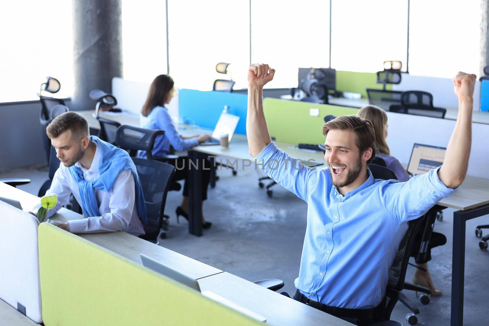 Businessman with arms raised celebrating success recived good news on e-mail in office. by tsyhun