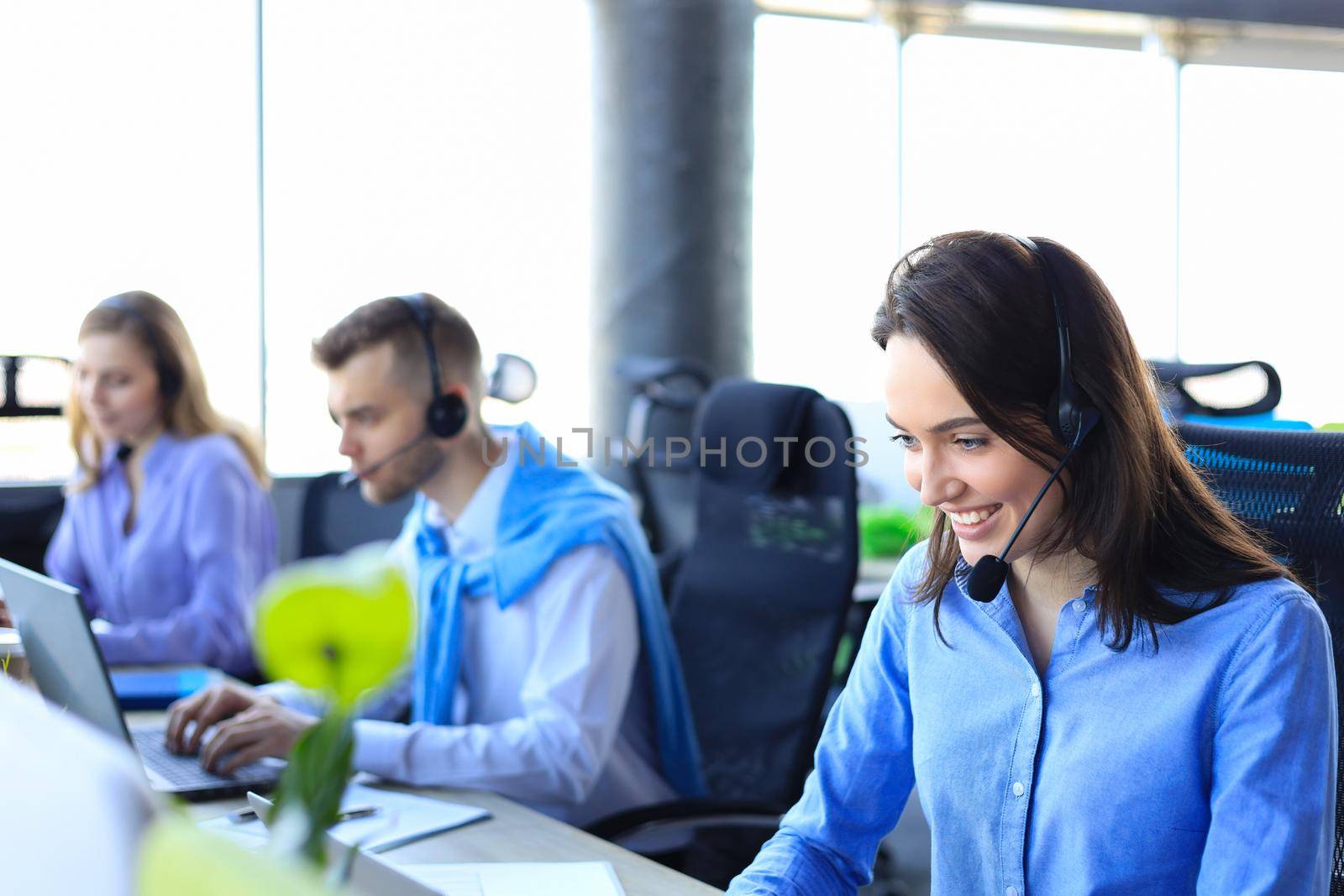 Smiling call center employees sitting in line with their headset