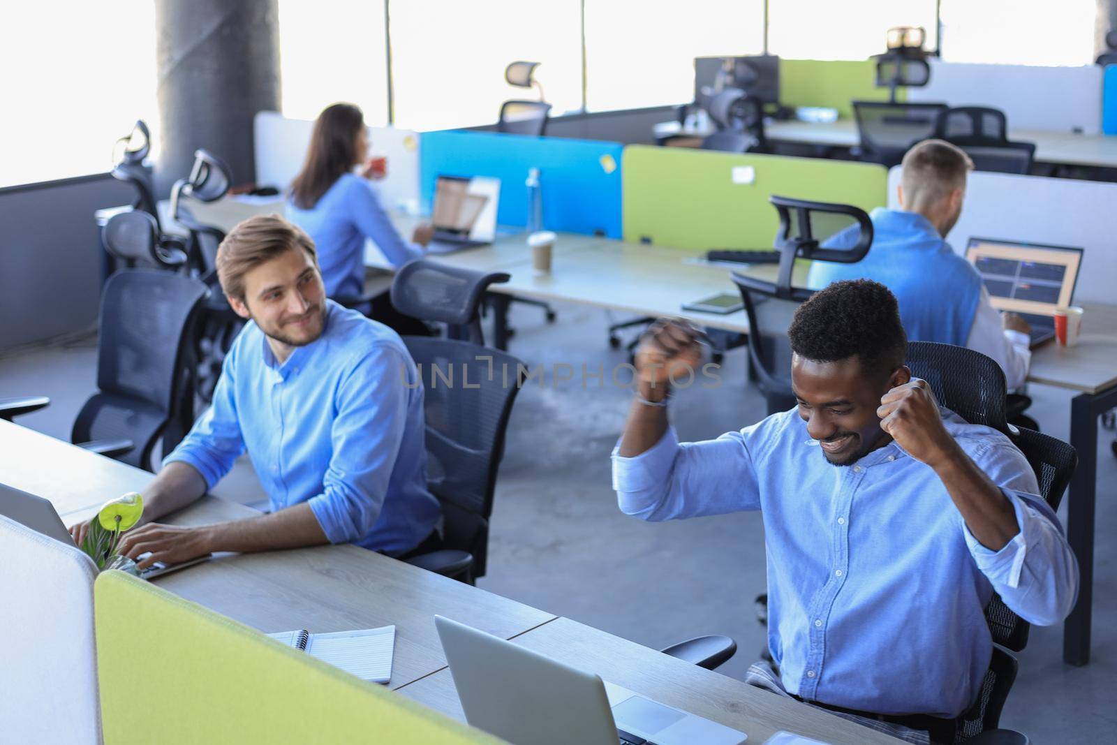 Businessman with arms raised celebrating success recived good news on e-mail in office. by tsyhun