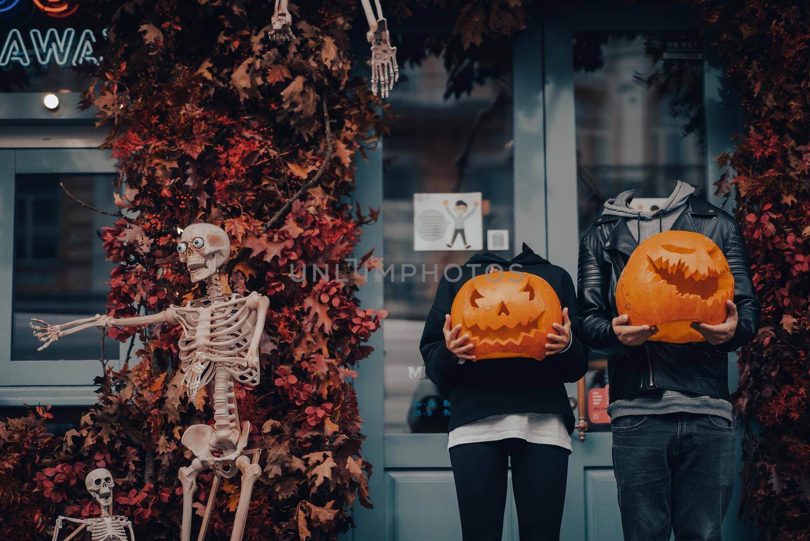Headless couple holding pumpkin heads by the door on the street . Halloween Concept
