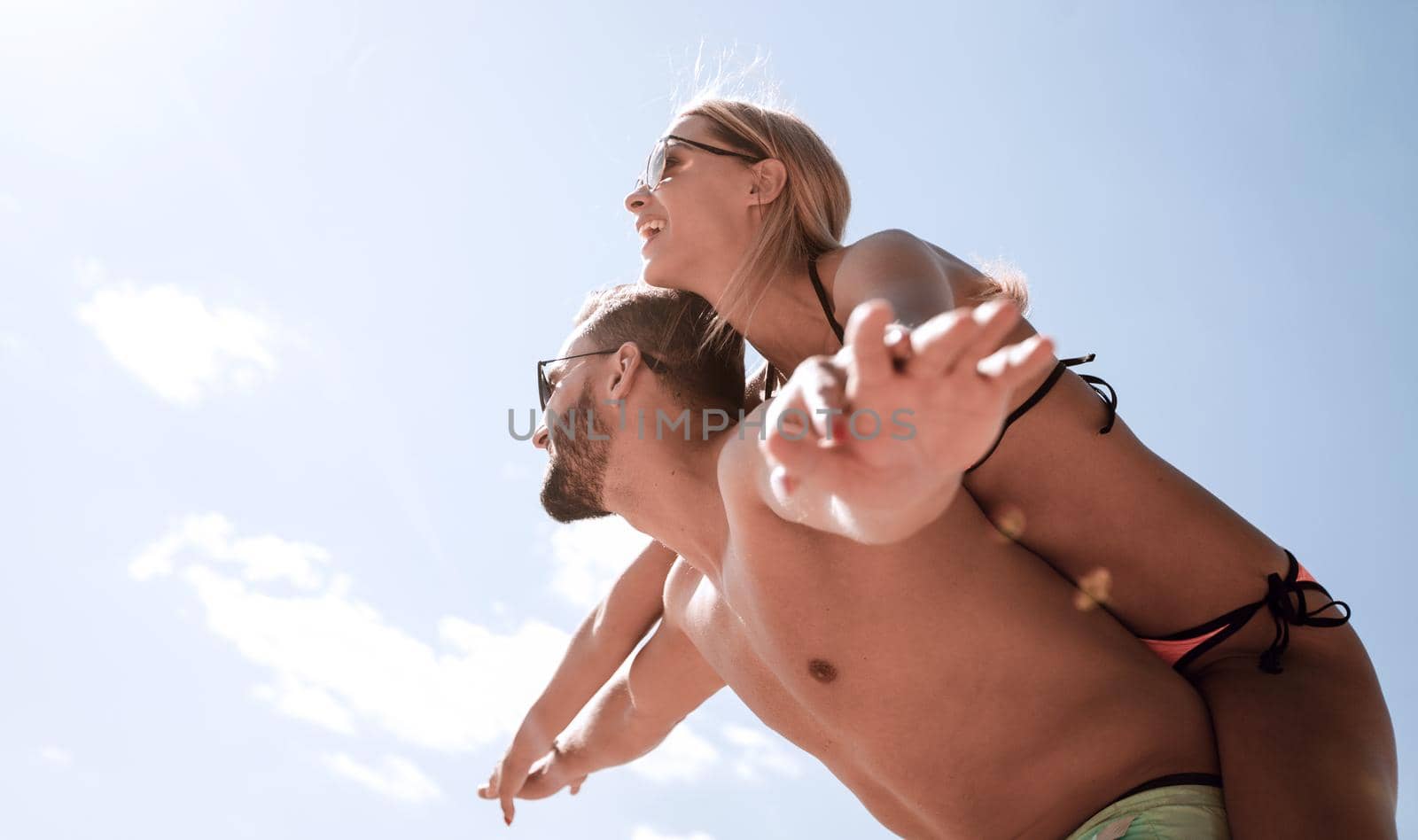 Handsome man giving piggy back to his girlfriend.