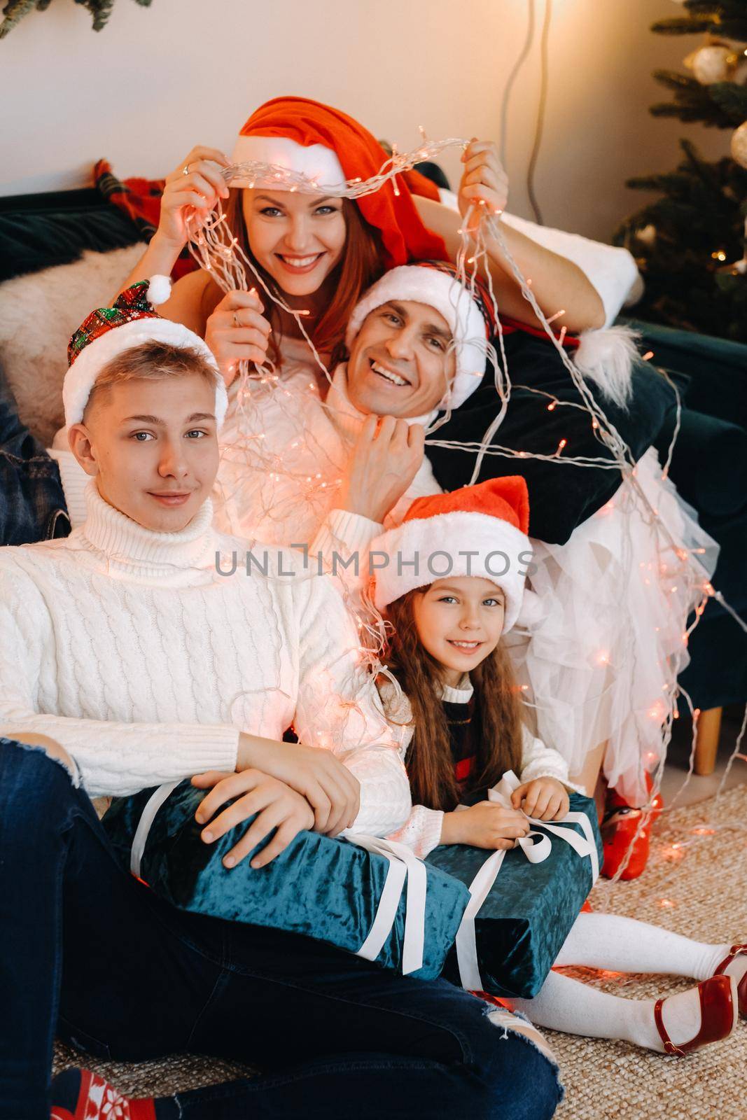 Close-up portrait of a happy family sitting on a sofa near a Christmas tree celebrating a holiday.