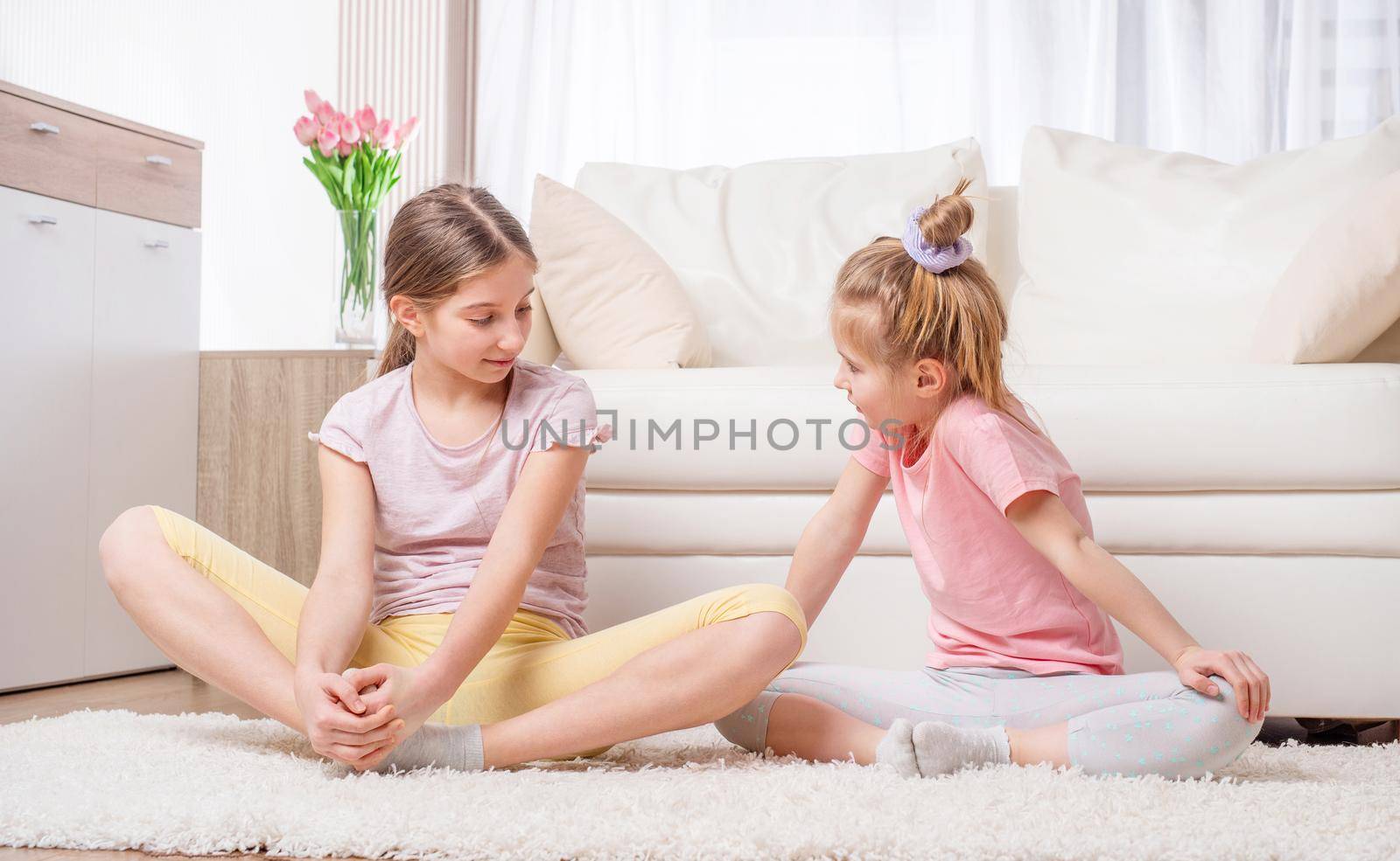 Two yoga-practicing girls are meditating with joy at home