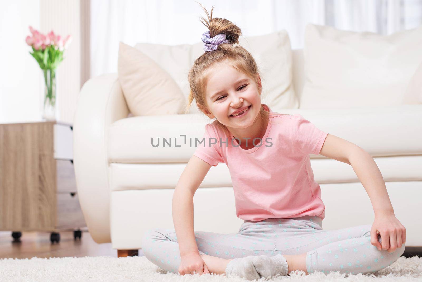 Cutie preteen kid sitting in relaxing yoga pose in bright room