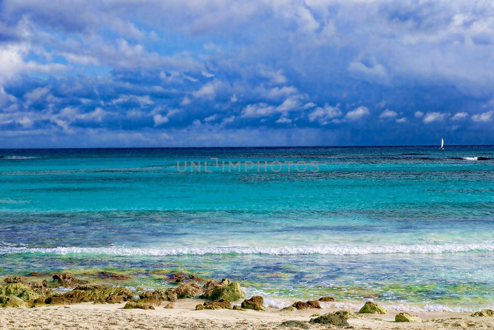 The view from the shore of a beautiful tropical sea with a beach. The warm waters of the ocean bathe colorful stones in the water. Vacation concept.