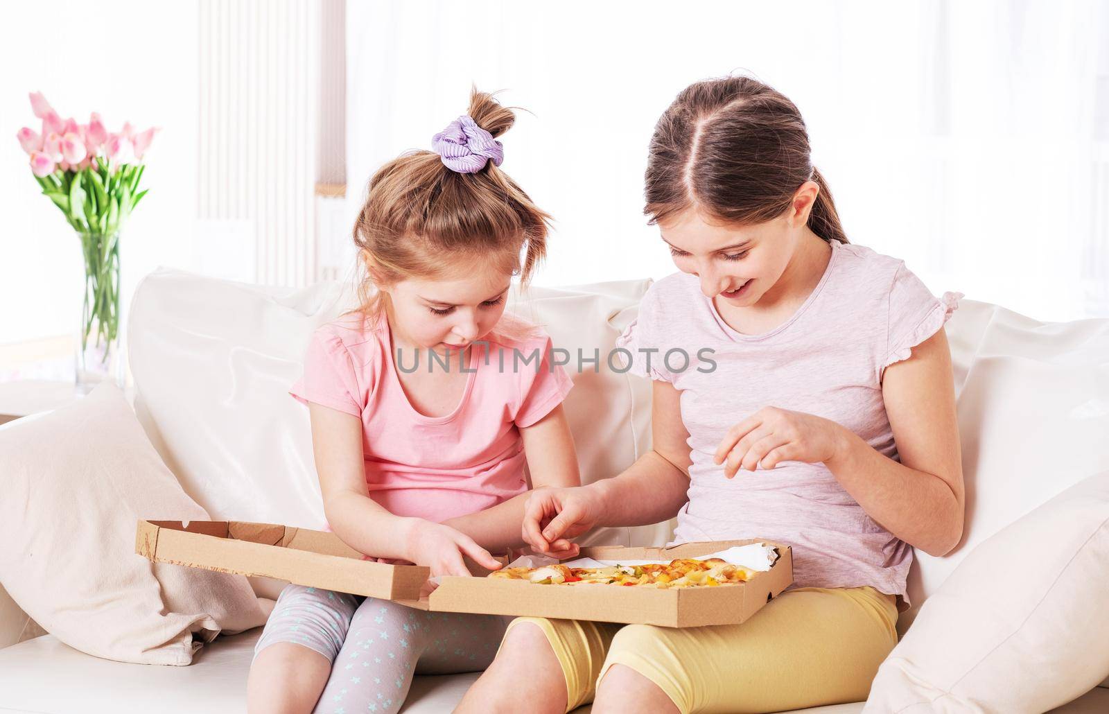 Two pretty sisters are enjoying tasty pizza for lunch